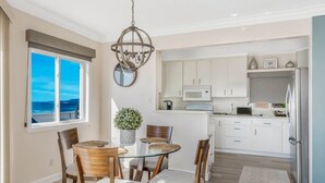 A modern kitchen with white cabinets, a stainless steel refrigerator, and a dining area with wooden chairs and a glass table. - Oceanfront with incredible views.
Last minute discounts Available (San Diego)