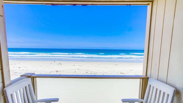 A beach view from a balcony with two white chairs. - Awesome ocean front condo in the heart of Mission Beach! (San Diego)