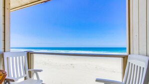 A beach view from a room with two white chairs and a table. - Awesome ocean front condo in the heart of Mission Beach! (San Diego)