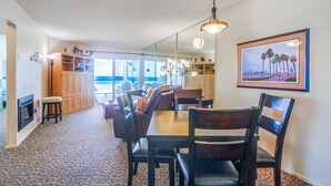 A dining area with a large table and chairs, a fireplace, and a view of the outdoors. - Awesome ocean front condo in the heart of Mission Beach! (San Diego)