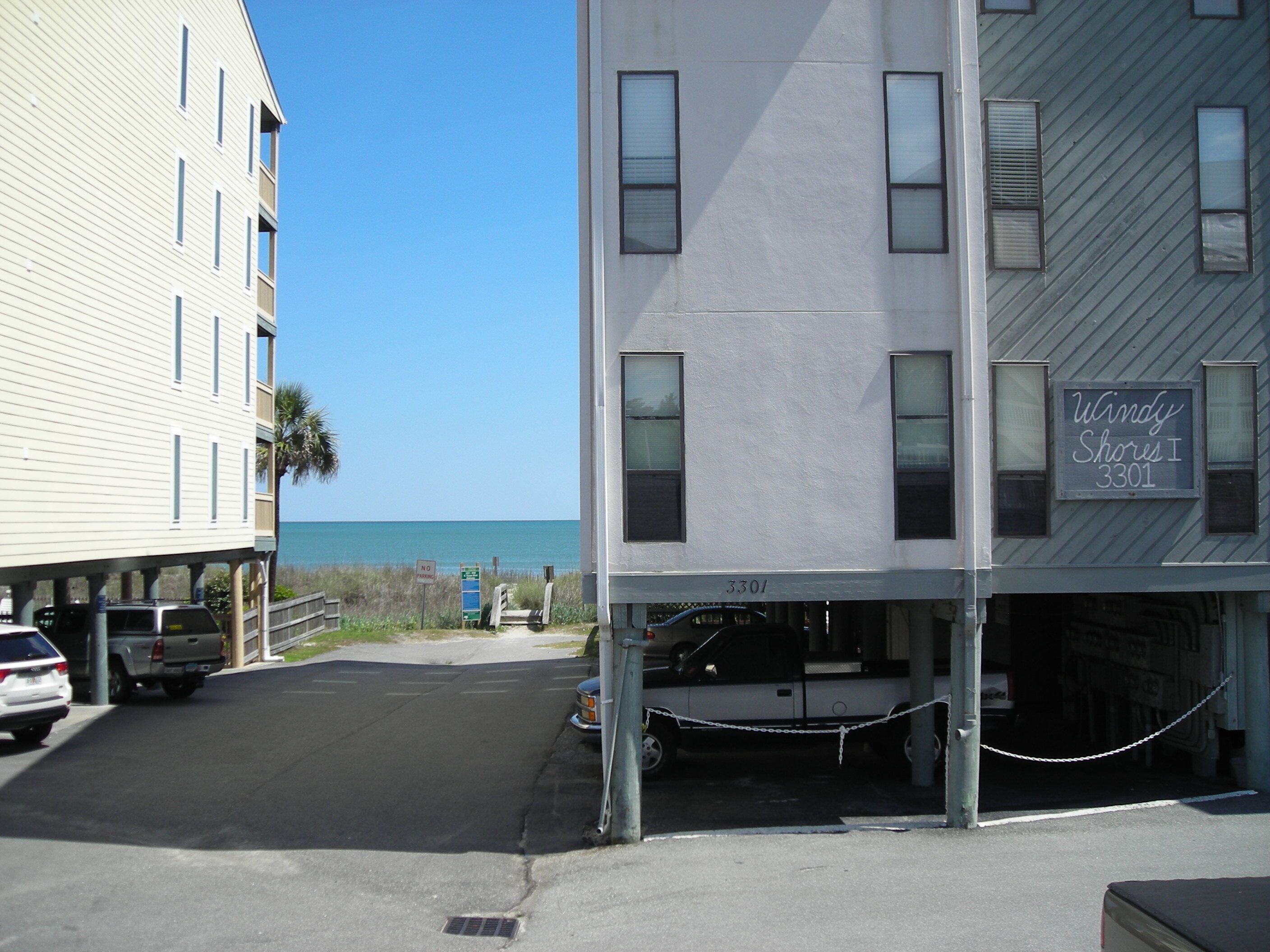 A building with a sign reading "Windy Shores I 3301" and a parking area with a chain barrier.