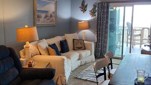 Ein Wohnzimmer mit einer Couch, zwei Lampen, einem Couchtisch und einem Esstisch mit Stühlen.