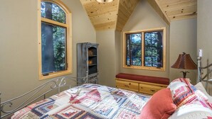 Una camera da letto con un letto, due finestre, una lampada e un soffitto in legno.