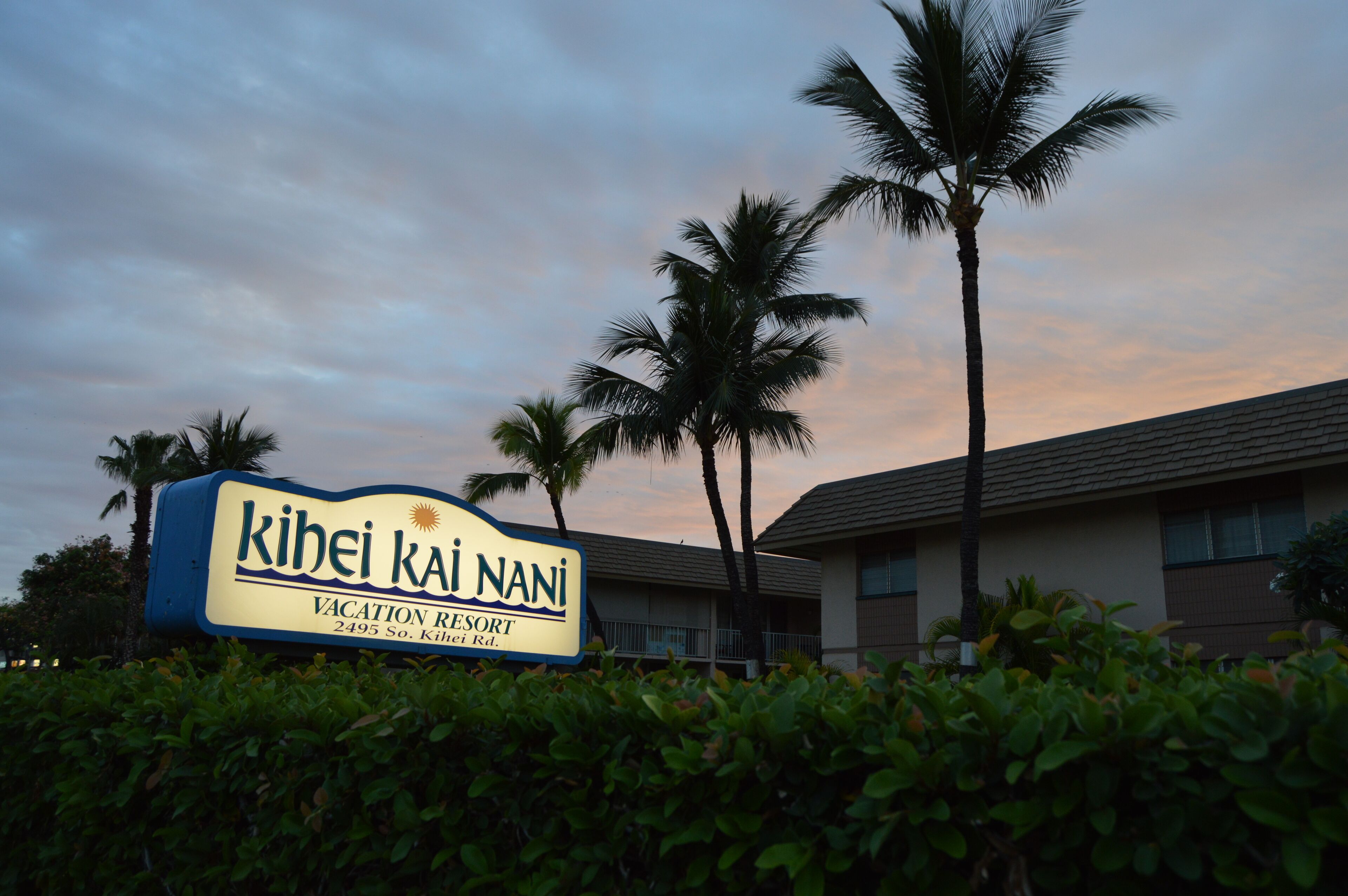 Señal para el Resort Vacacional Kihei Kai Nani, con cielo despejado y palmeras al fondo.
