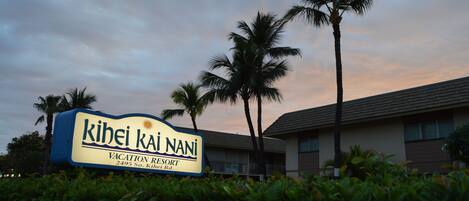 Señal para el Resort Vacacional Kihei Kai Nani, con cielo despejado y palmeras al fondo.