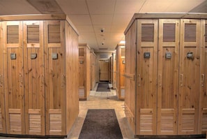 Une rangée de casiers en bois, chacun portant un numéro, qui mène à une porte au bout.