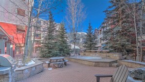 An outdoor patio area with brick flooring, picnic tables, and a barbecue grill. - SM8175, Heart of River Run Village! (Keystone)