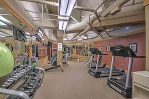 Un gimnasio con cintas de correr, mancuernas y equipamiento para hacer ejercicio.