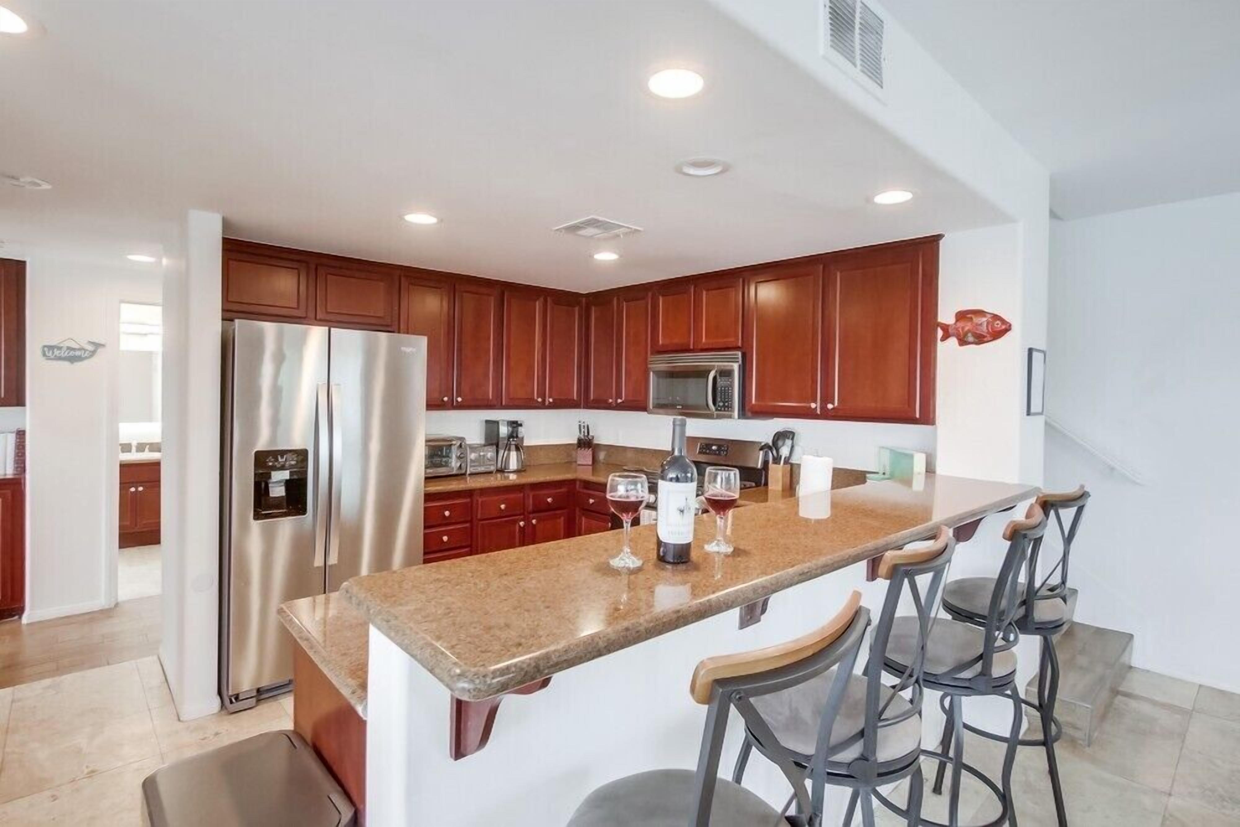 A modern kitchen with a central island, stainless steel appliances, and wooden cabinets.