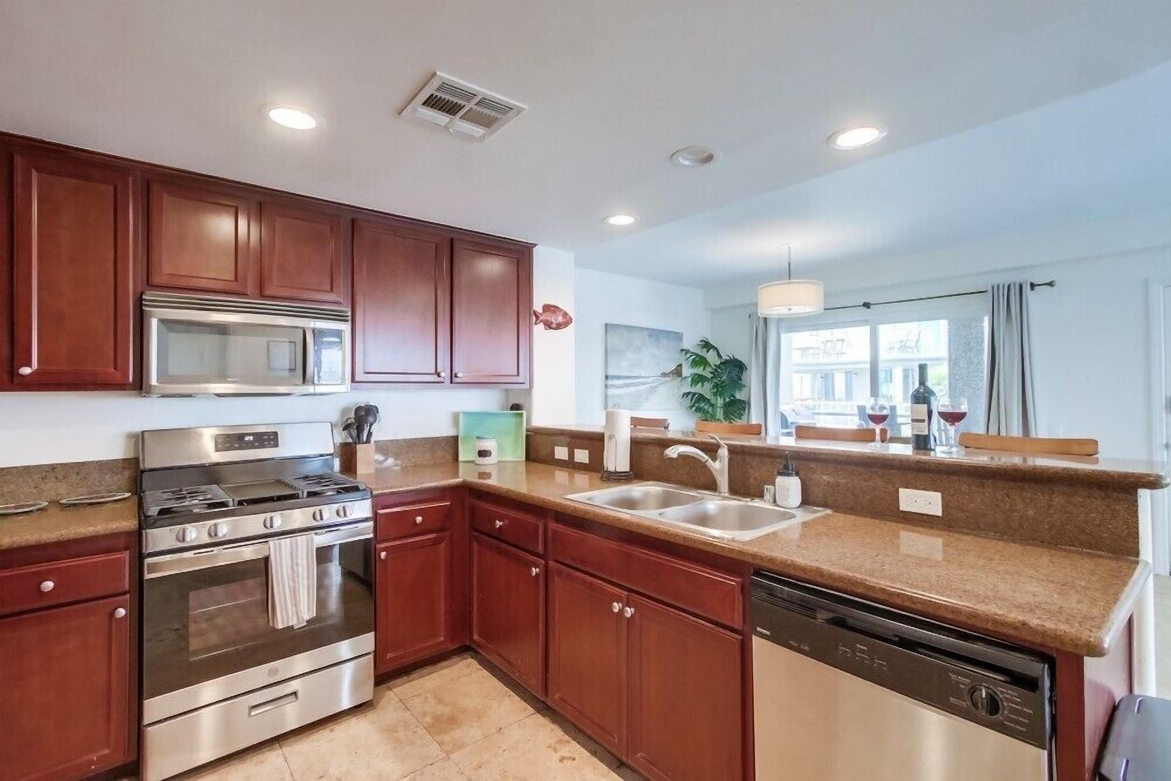 A modern kitchen with stainless steel appliances, wooden cabinets, and a granite countertop.