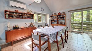 A dining area with a table, chairs, and shelves with various items. - Cozy 3 bedroom 2 bath beach house with private setting! Pool, Trolley, Wifi, Beach Town! (Bethany Beach)
