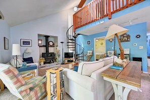 Ein Wohnzimmer mit Sofa, Sesseln, einem Holztisch und einer Wendeltreppe.