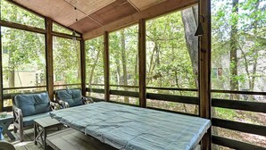 A covered outdoor seating area with a bed, chairs, and a table. - Cozy 3 bedroom 2 bath beach house with private setting! Pool, Trolley, Wifi, Beach Town! (Bethany Beach)
