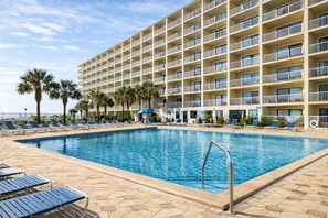 A hotel with a swimming pool, lounge chairs, and palm trees. - Beachy Gulf-View 1BR on the 14th Floor with Seasonal Beach Chairs at the Summit (Panama City Beach)