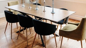 A dining area with a long table, black and green chairs, and a unique chandelier.
