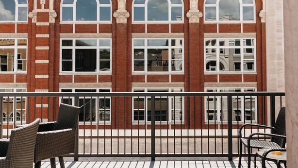 A building with arched windows and a balcony with wicker furniture.