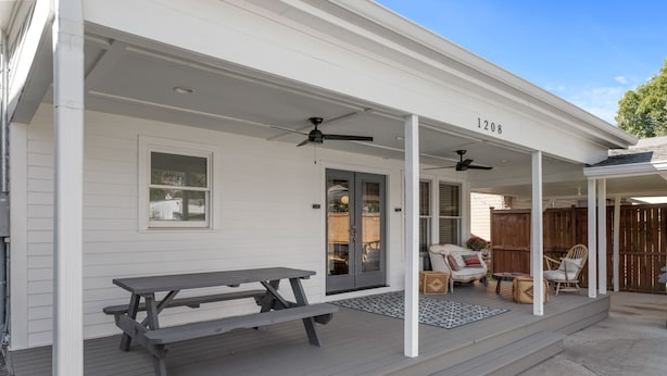 A covered porch with a picnic table, two ceiling fans, and a wooden fence in the background. - Heart of 12th South -  1 bed, 1 bath Cozy Suite in Nashville (Nashville)