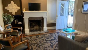 A living room with a fireplace, a television, and a sofa. - Budget Friendly Apartment on Jones Street! (Savannah)