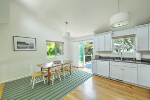 A modern kitchen with white cabinets, a wooden dining table, and a striped rug. - Fantastic Contemporary ,Min to Narr beach. (Narragansett)