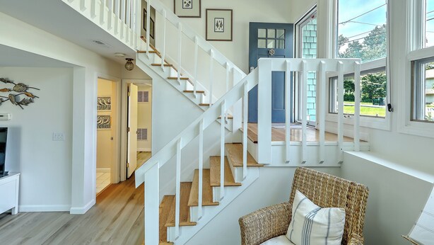 A spacious interior with a wooden staircase, a blue door, and a wicker chair. - Fantastic Contemporary ,Min to Narr beach. (Narragansett)