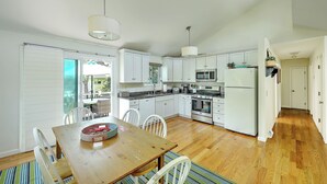 A modern kitchen with white cabinets, a wooden dining table, and a striped rug. - Fantastic Contemporary ,Min to Narr beach. (Narragansett)