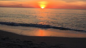 A sunset over a calm sea with a beach in the foreground. - Newer Upscale Home with Htd Pool & Spa - Bike or Walk to Beaches and Restaurants (Naples)