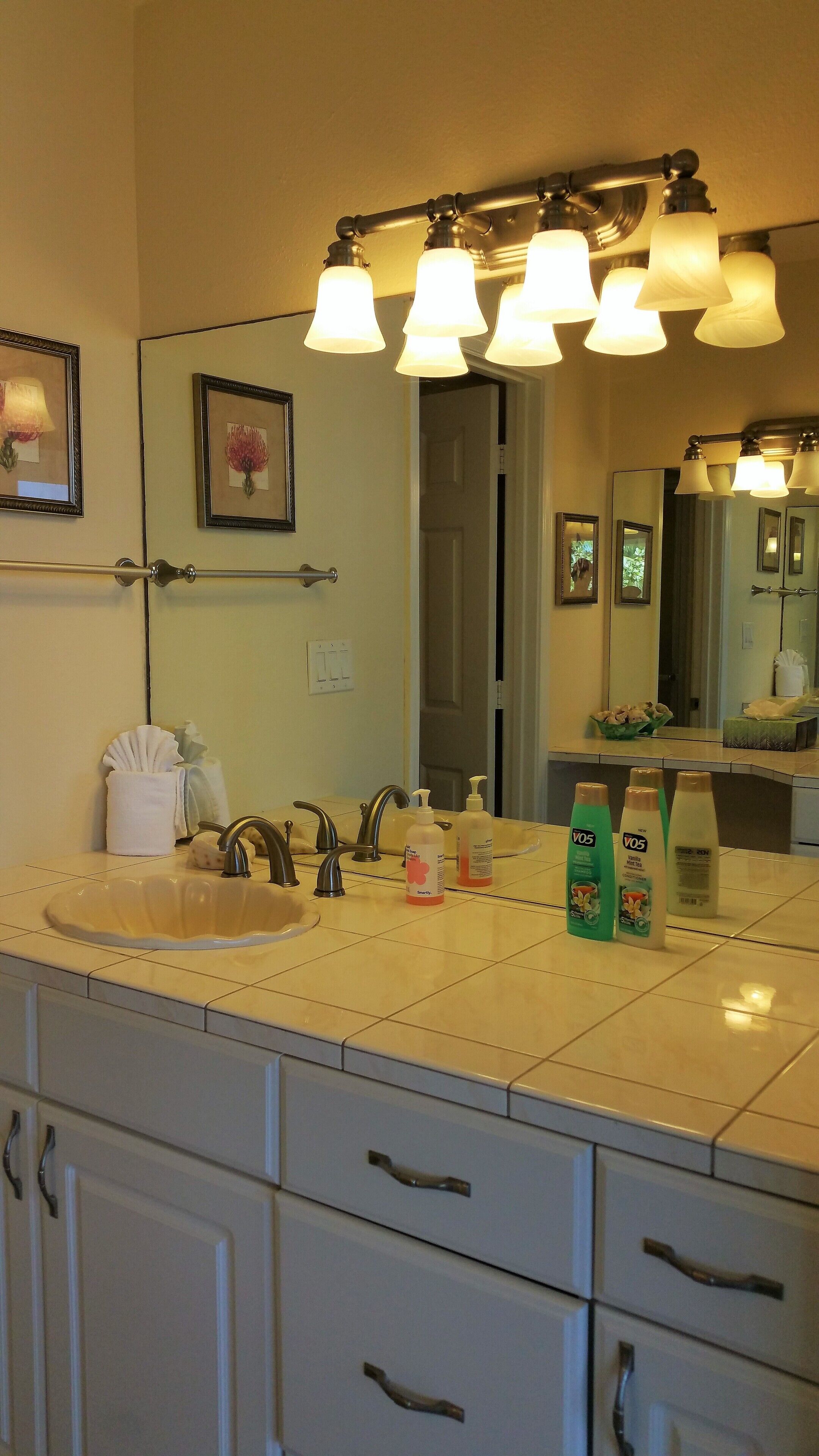 A bathroom with a sink, mirror, towel dispenser, and toiletries.