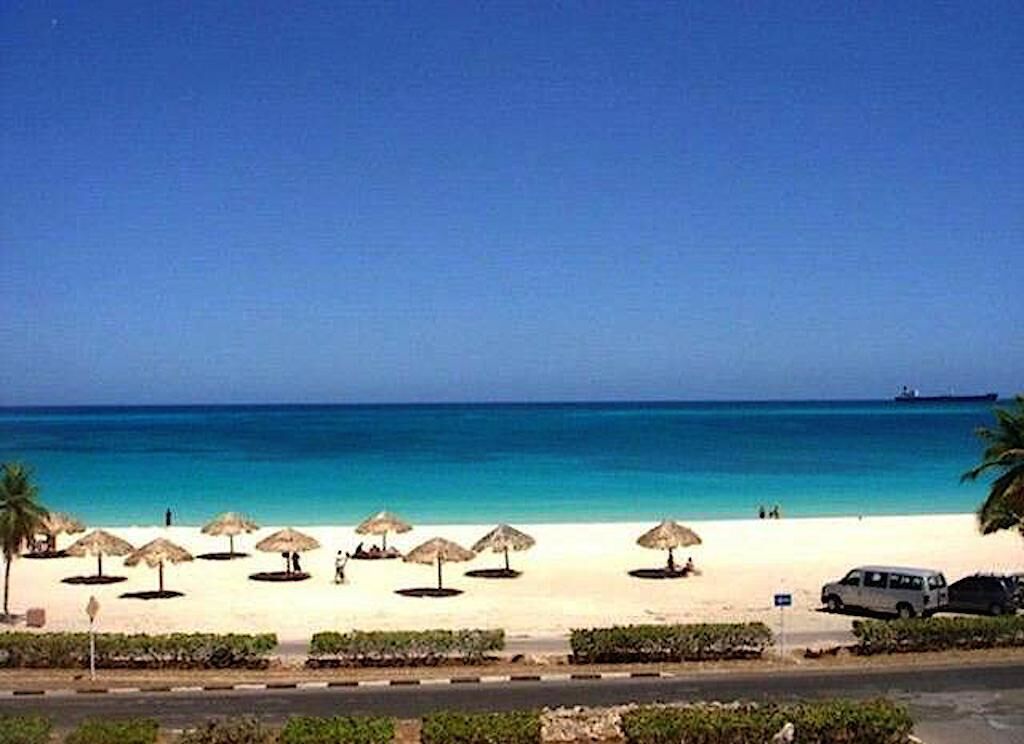 A beach with umbrellas and a van.