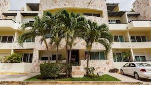 A multi-story building with a stone facade, palm trees in front, and a sign reading "THE MERIDIAN". - Meridian Beach Condo, 200m from beach and 5th avenue, Wifi (Playa Del Carmen)