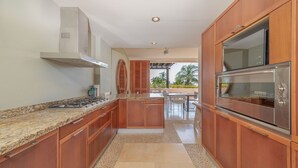 A modern kitchen with wooden cabinets, a stainless steel oven, and a granite countertop. - Ocean View Condo in Punta Mita, Beach Clubs access, Golf Cart, Breakfast, Pool. (PUNTA MITA)