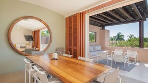 A modern dining area with a wooden table and white chairs, a large mirror, and a view of a balcony with outdoor seating. - Ocean View Condo in Punta Mita, Beach Clubs access, Golf Cart, Breakfast, Pool. (PUNTA MITA)