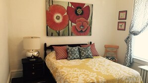 A bedroom with a bed, a nightstand, a lamp, a painting, and a window with curtains. - Apartment in the heart of Marquette w/ cable & wifi!!  Next to premier brewpub!! (Marquette)