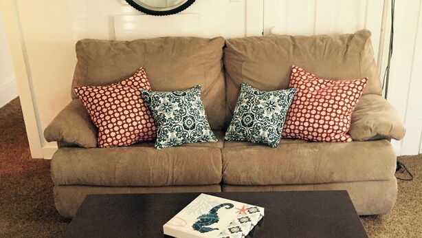 A living room with a beige sofa, patterned cushions, a black coffee table, and a striped rug. - Apartment in the heart of Marquette w/ cable & wifi!!  Next to premier brewpub!! (Marquette)