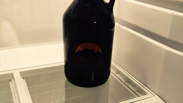 A dark-colored bottle with a handle on a glass shelf inside a white refrigerator.