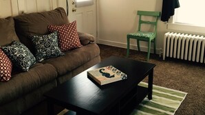 A living room with a brown sofa, a black coffee table, a green chair, and a striped rug. - Apartment in the heart of Marquette w/ cable & wifi!!  Next to premier brewpub!! (Marquette)