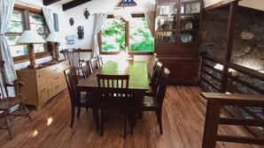 A dining area with wooden furniture, a green table, and a stone wall with a shelf. - Killington area home - 4-seasons, hot tub and A/C (Pittsfield)