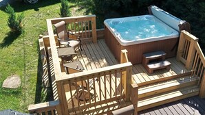 A wooden deck with a hot tub, outdoor seating, and a small table. - Killington area home - 4-seasons, hot tub and A/C (Pittsfield)
