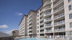 Ein mehrstöckiges Hotel mit Schwimmbad, Balkonen und blauem Himmel.
