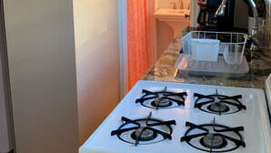 A kitchen with a white stove, a coffee maker, and a sink.
