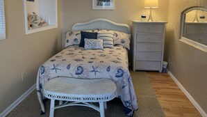 A bedroom with a bed, a dresser, a chair, a lamp, and a framed picture on the wall.