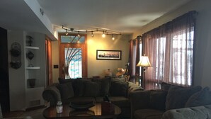 Un salon comprenant un ensemble de canapés, une table basse, une lampe et une fenêtre avec des rideaux.
