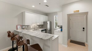 A modern kitchen with white cabinets, a marble island, and a built-in refrigerator. - Walking Distance to Snook Inn, Smith House, Shopping, Day Spa & Live Music! (Marco Island)