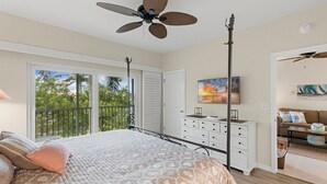A bedroom with a bed, a ceiling fan, a dresser, a painting, and a balcony with a view of trees. - Walking Distance to Snook Inn, Smith House, Shopping, Day Spa & Live Music! (Marco Island)