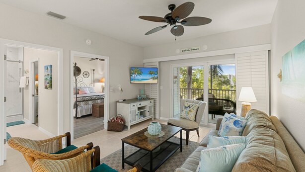 A spacious living area with a ceiling fan, a sofa, a coffee table, wicker chairs, and a television. - Walking Distance to Snook Inn, Smith House, Shopping, Day Spa & Live Music! (Marco Island)