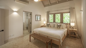 A bedroom with a large bed, a bench, a bedside table with a lamp, and a window with curtains. - ATTRACTIVE RATES JUST REMODELED  - Near Beach 4 BD Amazing Golf View Villa (La Romana)