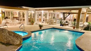 A swimming pool with a stone accent wall, surrounded by outdoor seating and a covered patio area. - ATTRACTIVE RATES JUST REMODELED  - Near Beach 4 BD Amazing Golf View Villa (La Romana)