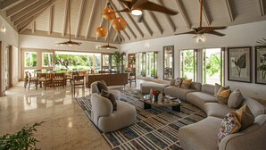 A spacious living area with a high ceiling, ceiling fans, and large windows offering views of greenery. - ATTRACTIVE RATES JUST REMODELED  - Near Beach 4 BD Amazing Golf View Villa (La Romana)
