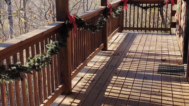 A wooden deck with a railing, decorated with garlands and red bows. -  Decorated for Country Christmas 2 BR & 2 BA Loft Crib & Highchair Wi-Fi no pets (Pigeon Forge)