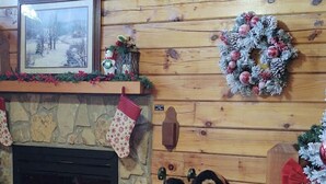 A cozy room with a stone fireplace, a Christmas wreath, a teddy bear, and a small Christmas tree. -  Decorated for Country Christmas 2 BR & 2 BA Loft Crib & Highchair Wi-Fi no pets (Pigeon Forge)