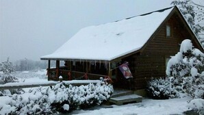 A wooden cabin with a snow-covered roof and a porch. -  Decorated for Country Christmas 2 BR & 2 BA Loft Crib & Highchair Wi-Fi no pets (Pigeon Forge)